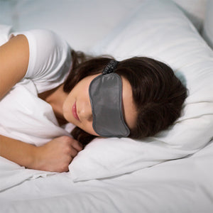 Sleeping woman wearing dark gray satin eye mask