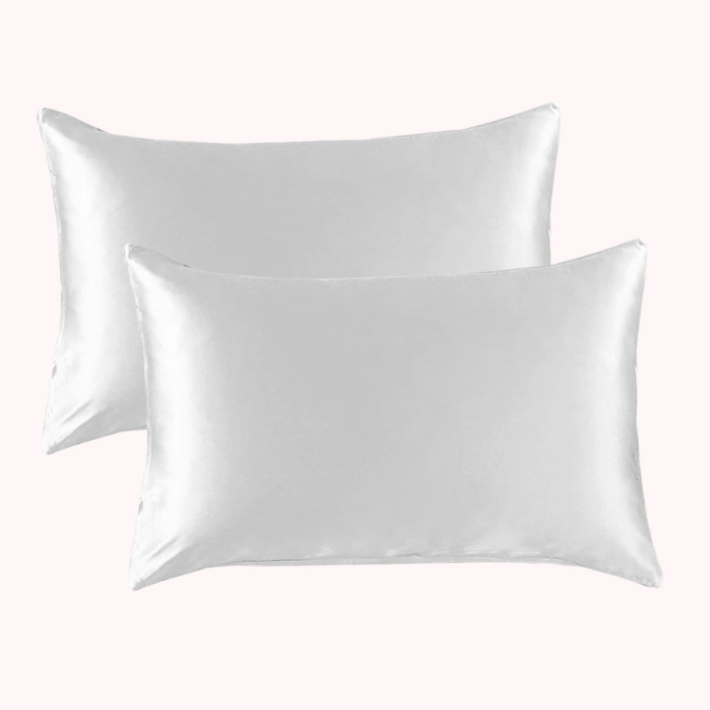 2 pillows encased in white satin pillowcases