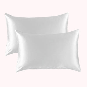 2 pillows encased in white satin pillowcases